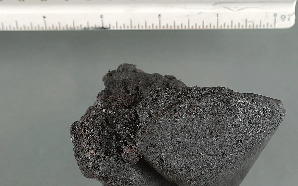 Ciemna lepka bryła heroiny black tar obok linijki